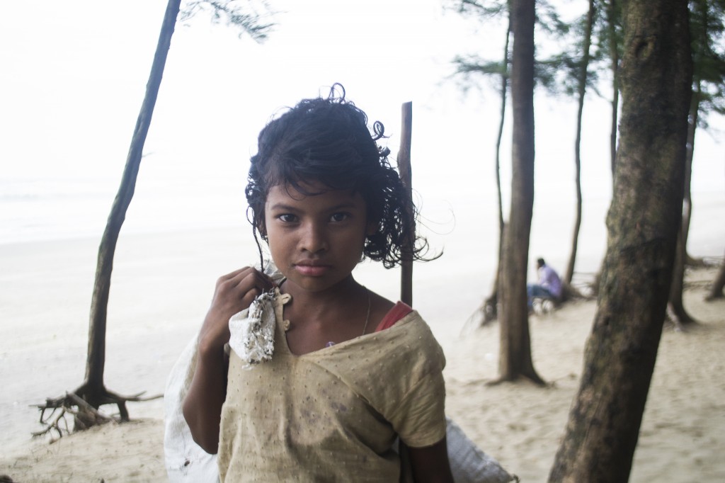 Bangladesh girl picking up trash at the beach